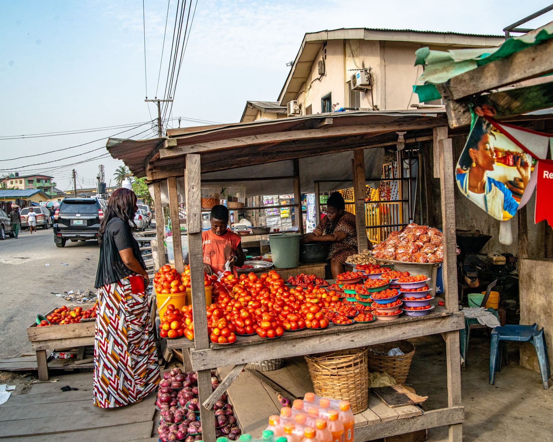 A roadside produce stall stocked with tomatoes and onions